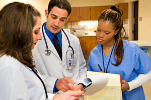 Three medical professionals looking at a clipboard and reviewing lab test results