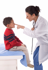 Smiling female medical provider in lab coat touching the nose of a small boy in a red sweater