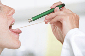 Healthcare provider using a tongue depressor and small flashlight to examine a female patient's throat in a Tampa health clinic