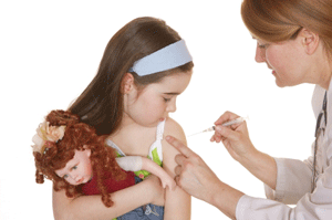 Little girl holding a doll while receiving a shot from a medical provider at a family health clinic