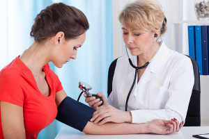 Doctor taking patient's blood pressure during physical exam