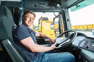 Smiling man sitting behind the steering wheel of a commercial truck