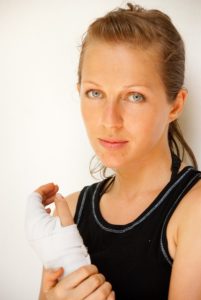 Woman in exercise clothes clutching her fractured wrist