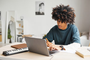 Male student using laptop while doing homework in college dorm