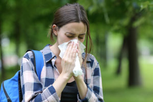 College student blowing her nose on campus